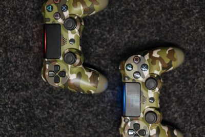 Close-up view of camouflage-patterned game controllers on a dark carpet background.